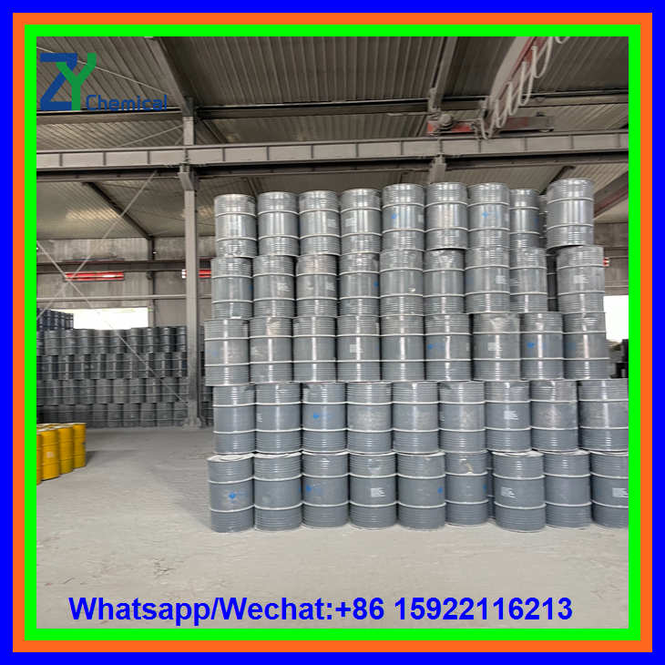 A high stack of grey industrial drums storing calcium carbide lumps positioned in an open area of a manufacturing factory floor.