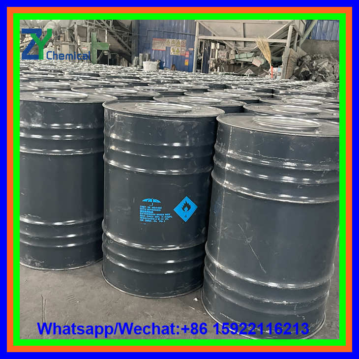A close-up view of steel drums filled with calcium carbide lumps, clearly showing the hazardous material warning labels and a protective umbrella symbol on the side.