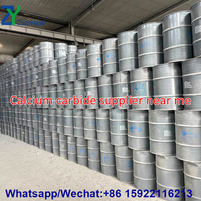 Locating nearby calcium carbide suppliers: Large quantities of standardized iron drums containing calcium carbide are neatly stacked in a spacious factory warehouse; ample stock is available, and shipments can be arranged at any time.